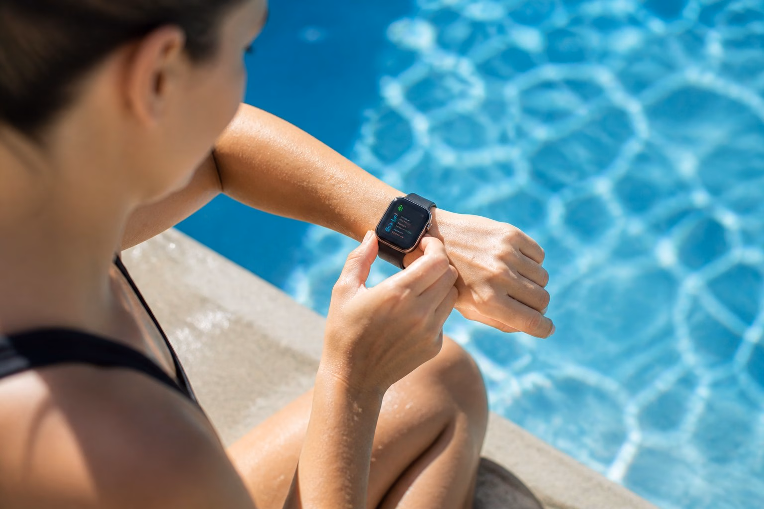 A person by the edge of a swimming pool wearing an Apple Watch, preparing to swim.