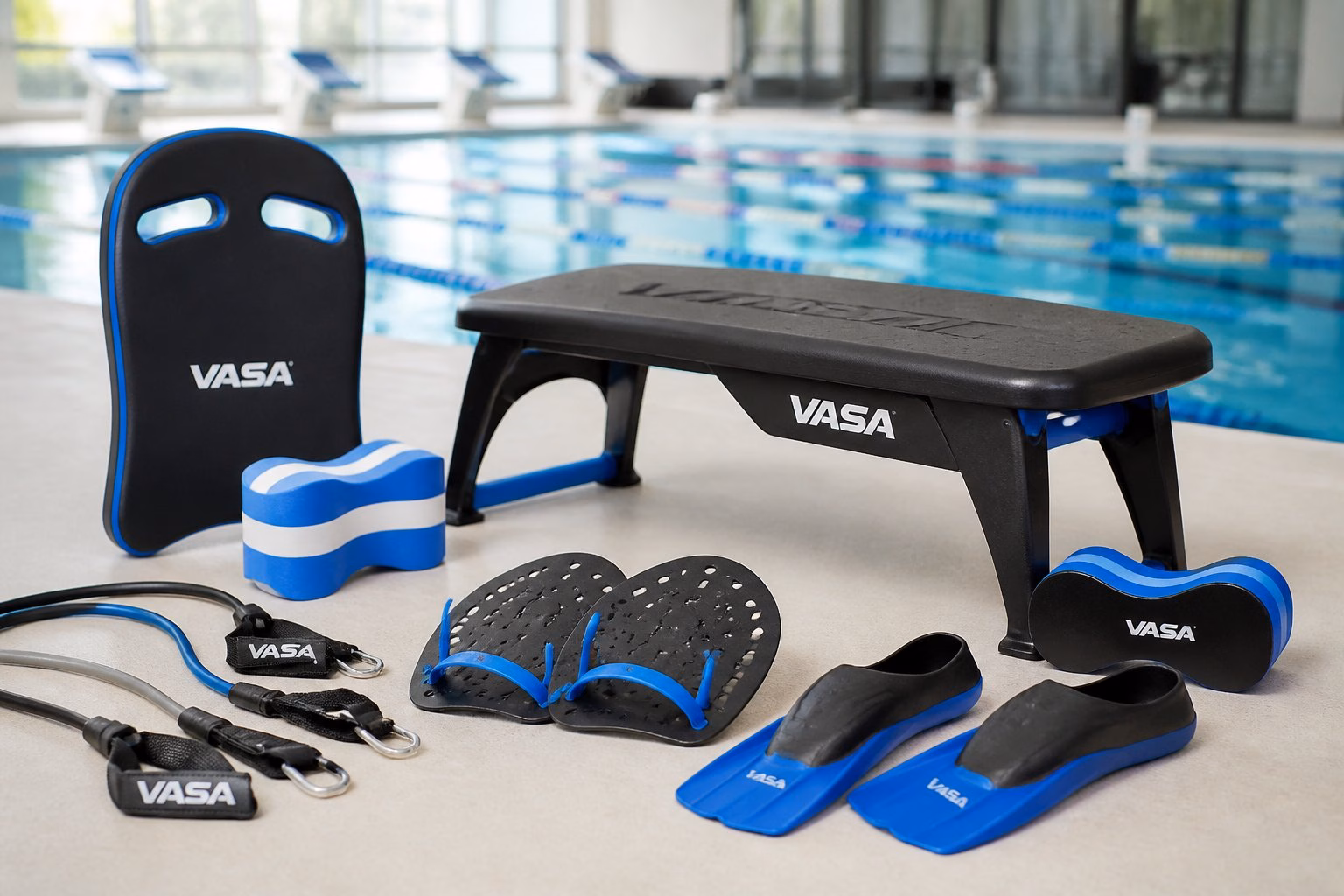 Swim strength training equipment including resistance bands, swim paddles, pull buoys, and fins arranged on a surface in a swimming pool training facility.