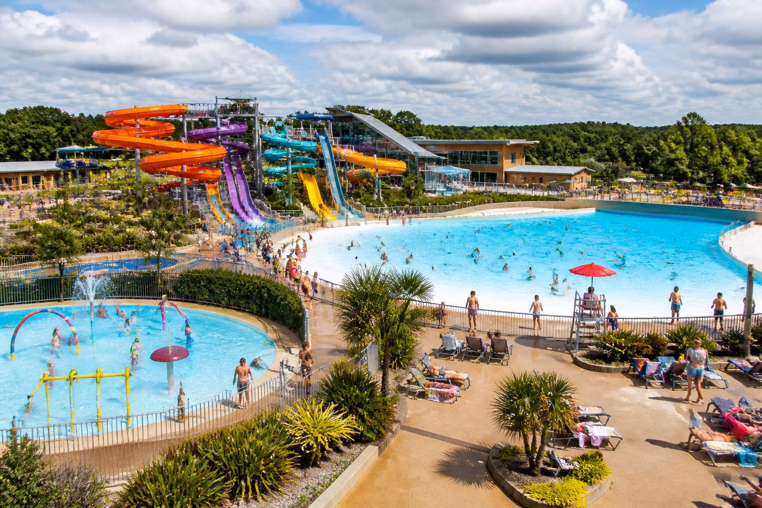 Families enjoying slides, pools and splash areas at a large outdoor water park.