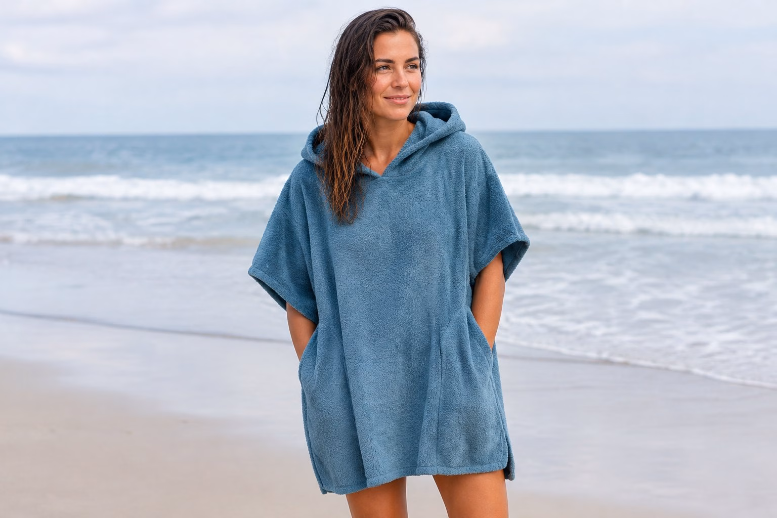 An adult wearing a surf poncho towel on a beach.