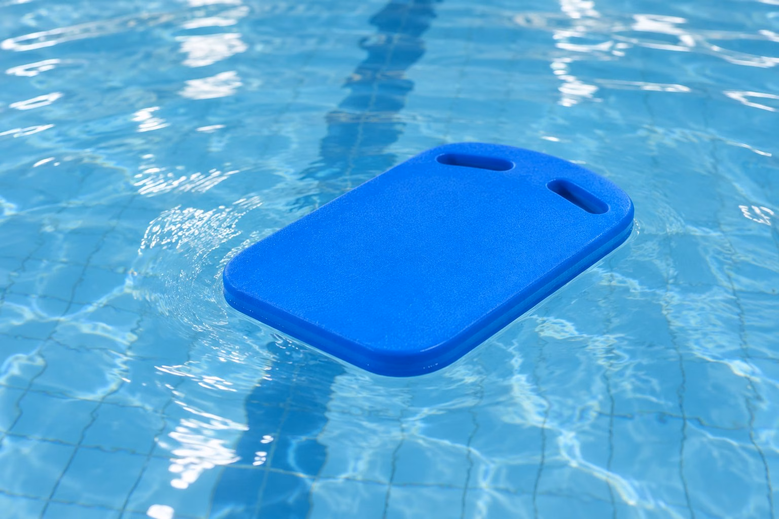 A blue swimming kickboard floating in a pool.