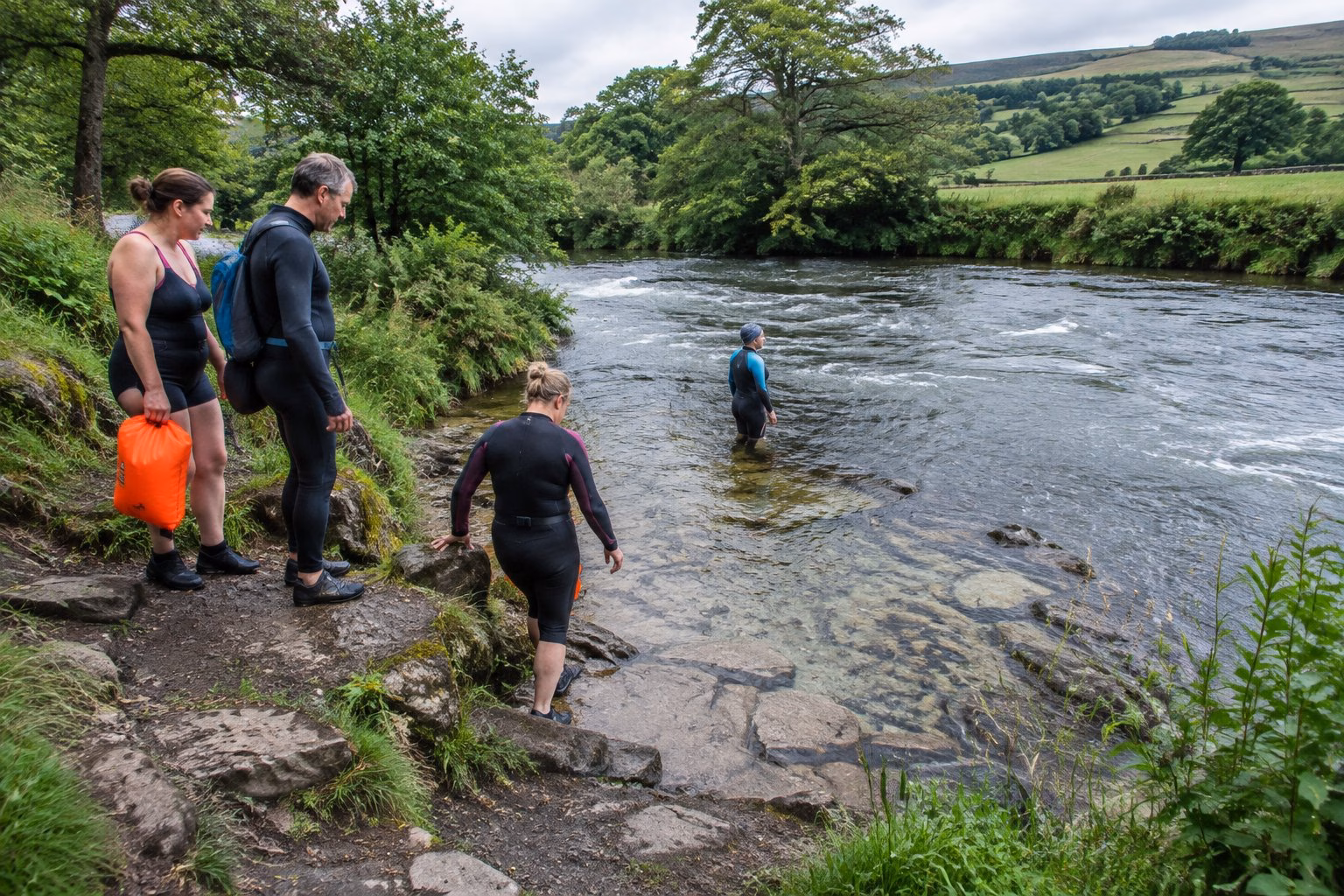Swimmers assess a riverside entry point in the Yorkshire countryside.